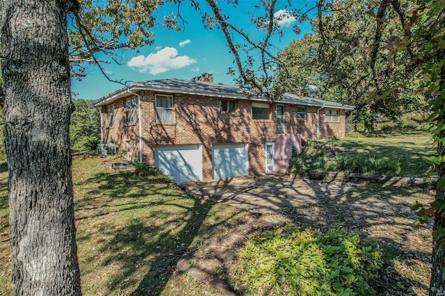 rear view of house featuring a lawn and a garage