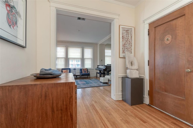 hallway featuring ornamental molding and light hardwood / wood-style floors