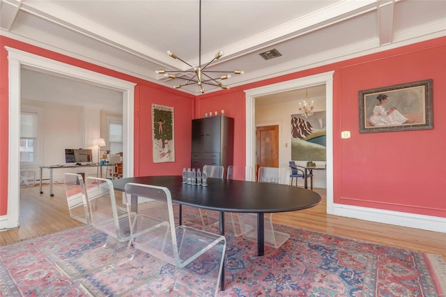 dining space with hardwood / wood-style flooring, an inviting chandelier, and ornamental molding