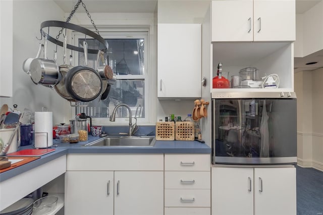 kitchen featuring stainless steel fridge, white cabinetry, and sink