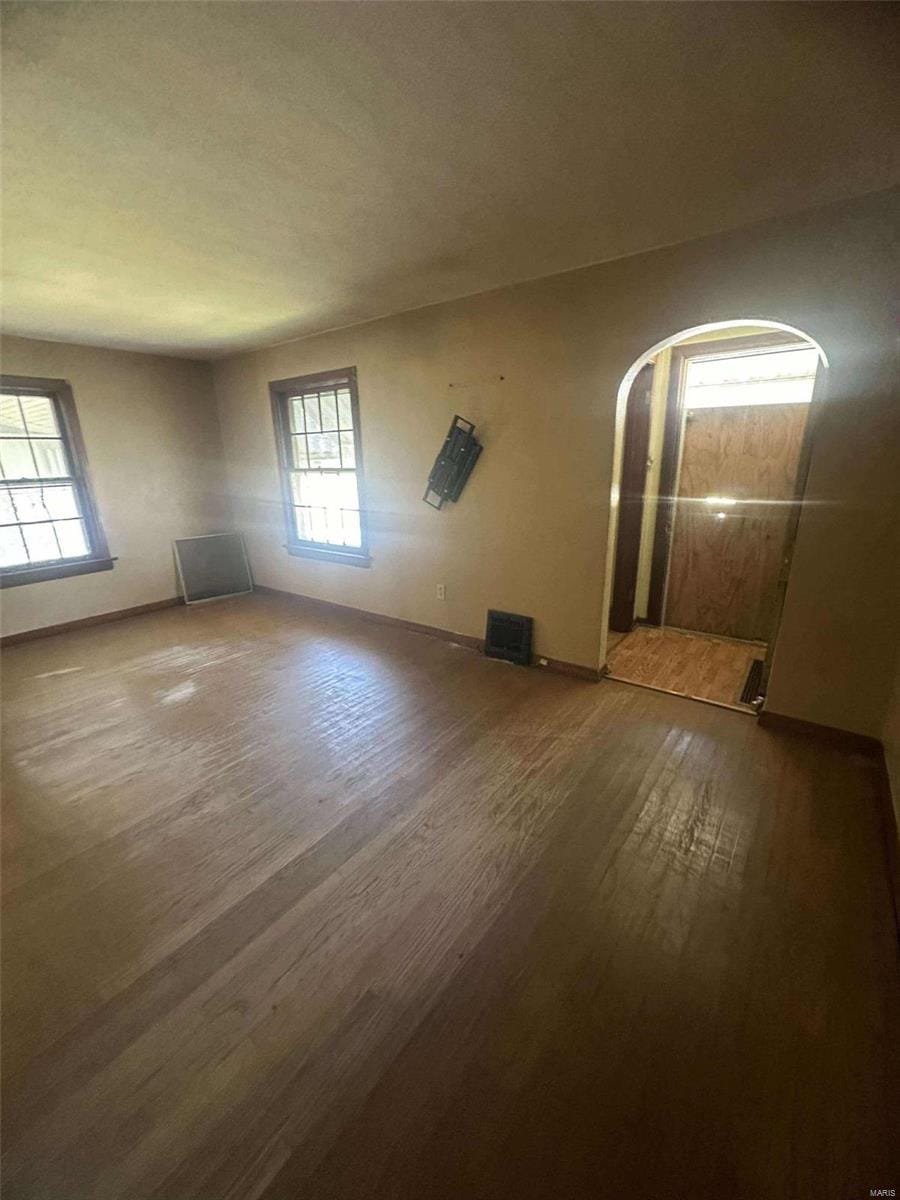 empty room with dark wood-type flooring and plenty of natural light