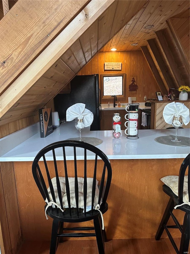 interior space featuring hardwood / wood-style floors, lofted ceiling, wood ceiling, sink, and wood walls