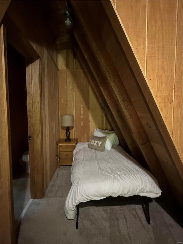 bedroom featuring vaulted ceiling, light carpet, and wooden walls