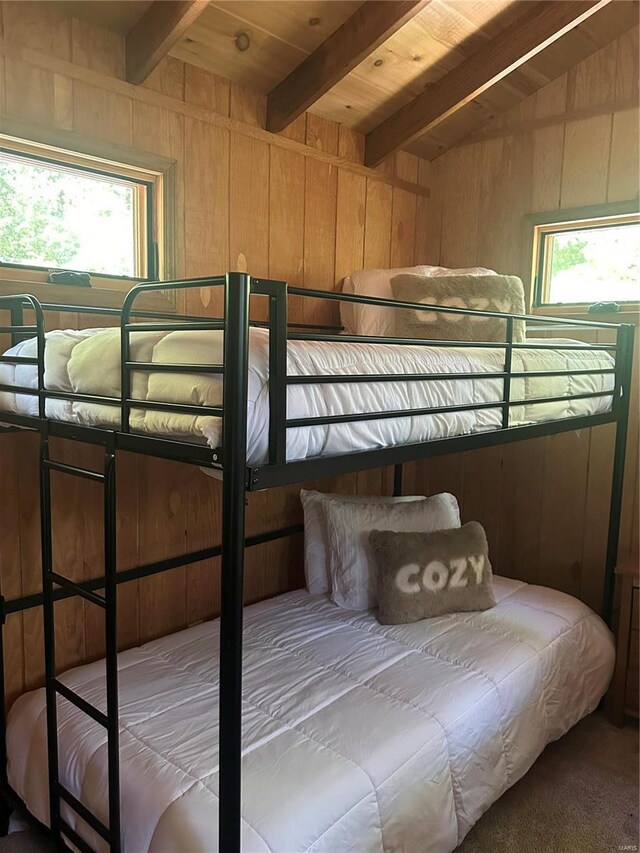 carpeted bedroom with wood walls, vaulted ceiling with beams, and wood ceiling