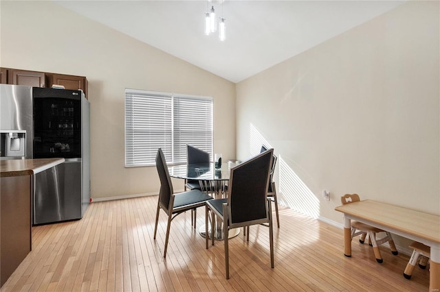 dining room featuring lofted ceiling and light hardwood / wood-style flooring