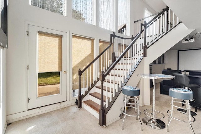 stairs with carpet floors and a towering ceiling