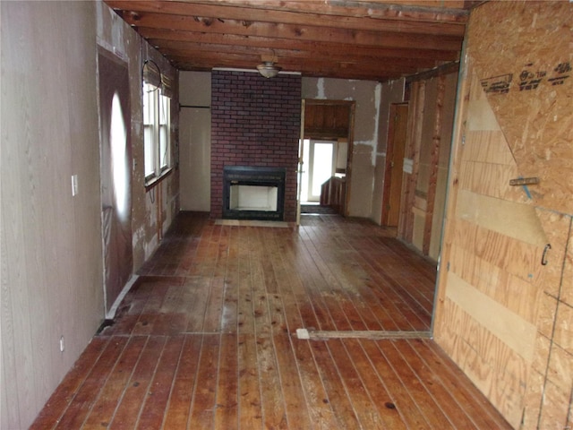 unfurnished living room with a fireplace, wood walls, dark hardwood / wood-style flooring, and plenty of natural light