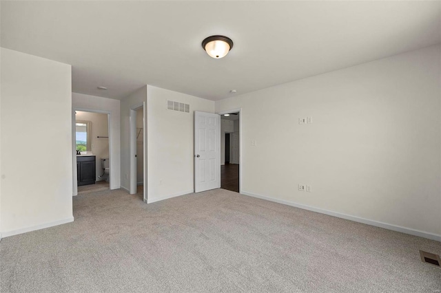 unfurnished bedroom featuring light colored carpet and ensuite bath