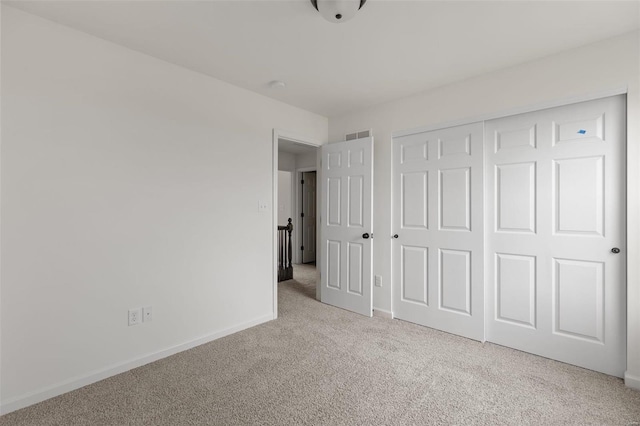 unfurnished bedroom with light colored carpet and a closet