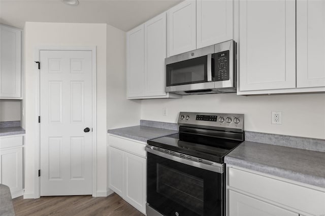 kitchen with stainless steel appliances, light hardwood / wood-style floors, and white cabinetry