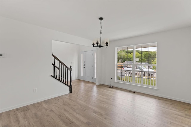 unfurnished dining area with a chandelier and light hardwood / wood-style flooring