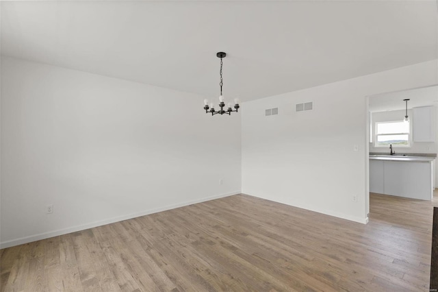 unfurnished dining area with an inviting chandelier and light hardwood / wood-style floors