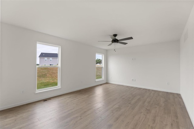 unfurnished room featuring a healthy amount of sunlight, ceiling fan, and light wood-type flooring