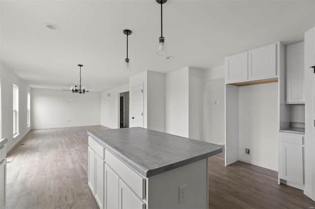 kitchen with dark wood-type flooring, pendant lighting, a center island, and white cabinetry