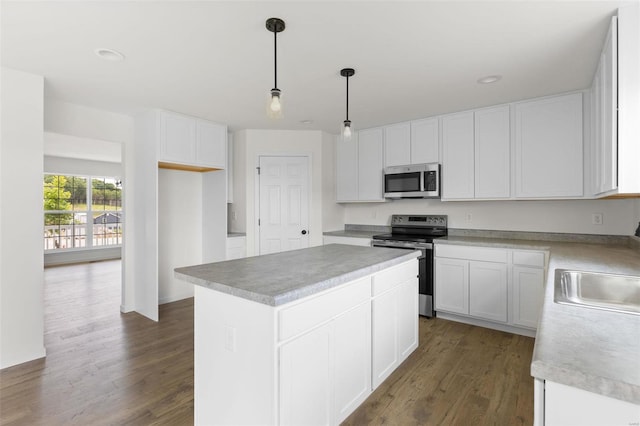 kitchen with decorative light fixtures, hardwood / wood-style floors, appliances with stainless steel finishes, a center island, and white cabinetry