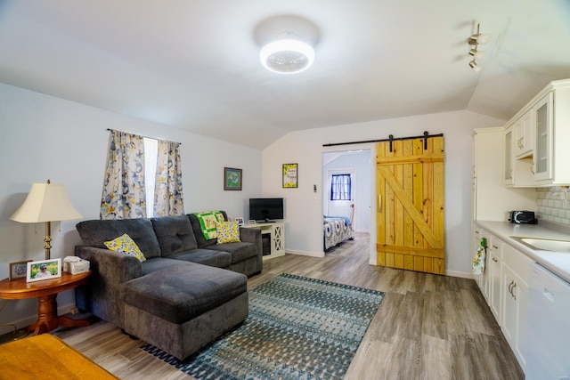 living room featuring a barn door, lofted ceiling, and light wood-type flooring