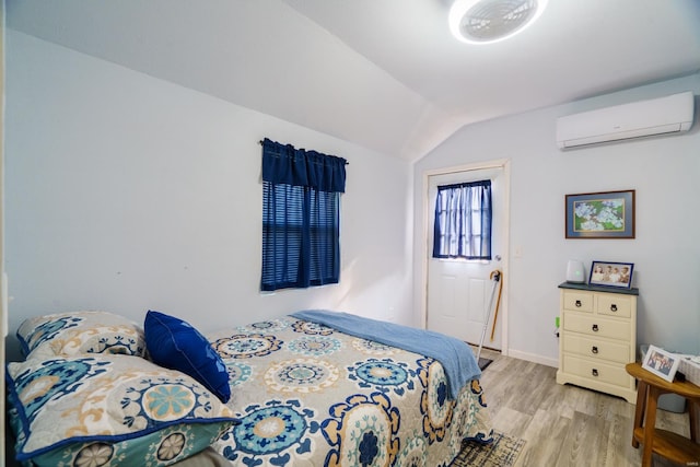 bedroom featuring a wall mounted AC, vaulted ceiling, and light hardwood / wood-style flooring