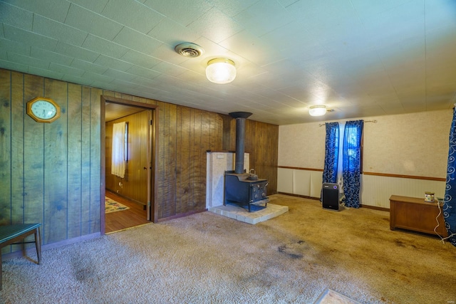 basement featuring a wood stove, carpet, and wooden walls