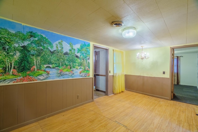 unfurnished room featuring wood-type flooring and a notable chandelier