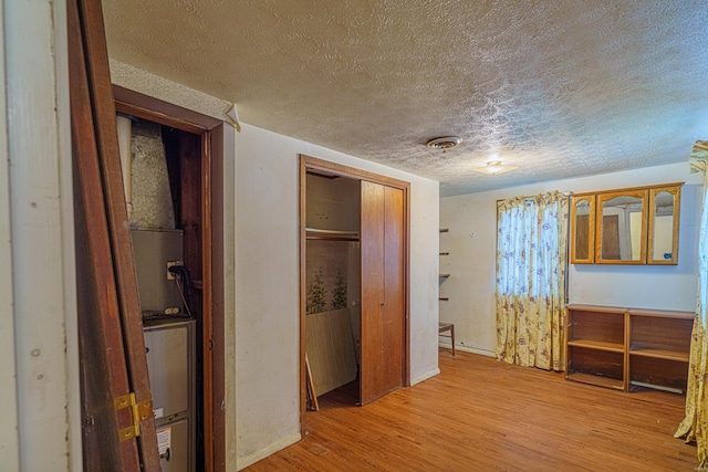 hall with light hardwood / wood-style floors and a textured ceiling