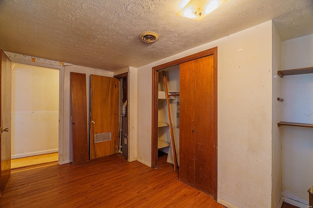 unfurnished bedroom with hardwood / wood-style flooring and a textured ceiling