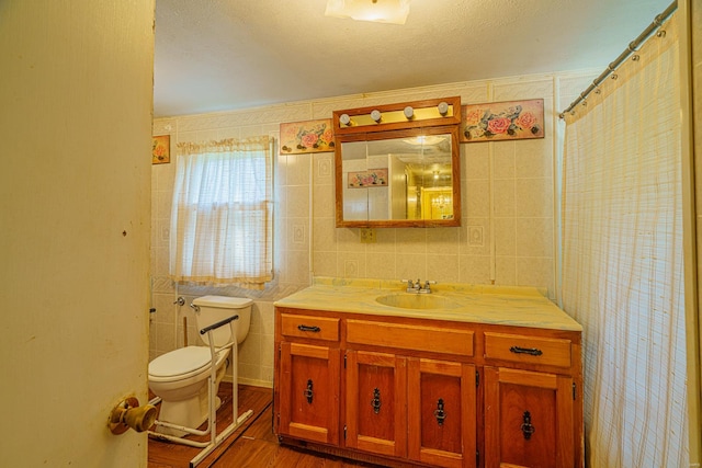 bathroom with a textured ceiling, vanity, tile walls, toilet, and hardwood / wood-style flooring