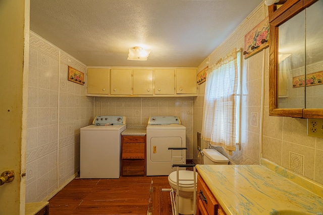 washroom with a textured ceiling, a healthy amount of sunlight, washer and clothes dryer, and dark hardwood / wood-style flooring