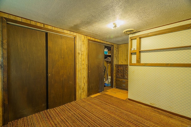 unfurnished bedroom with wood walls and a textured ceiling