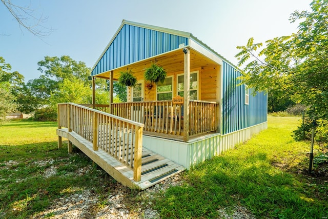 back of property featuring a wooden deck and a lawn