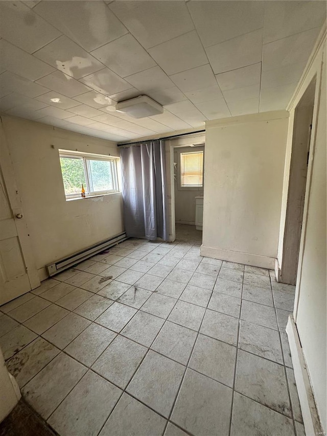 tiled empty room featuring baseboard heating