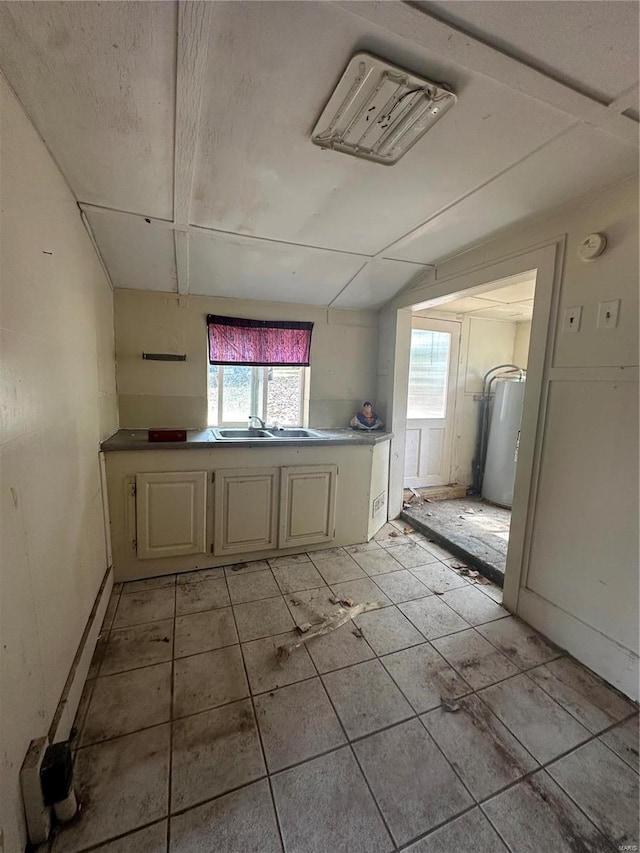 empty room featuring water heater and light tile patterned flooring