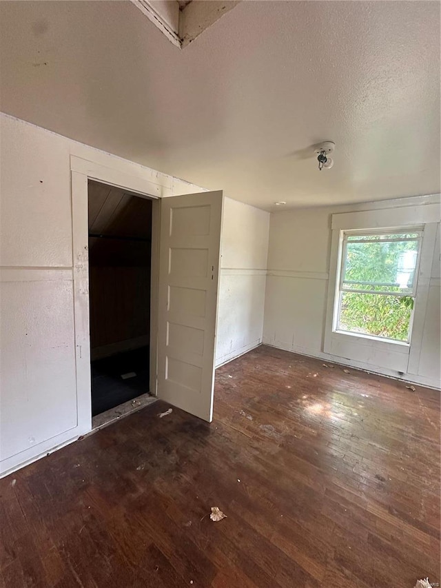 empty room with dark hardwood / wood-style flooring and a textured ceiling