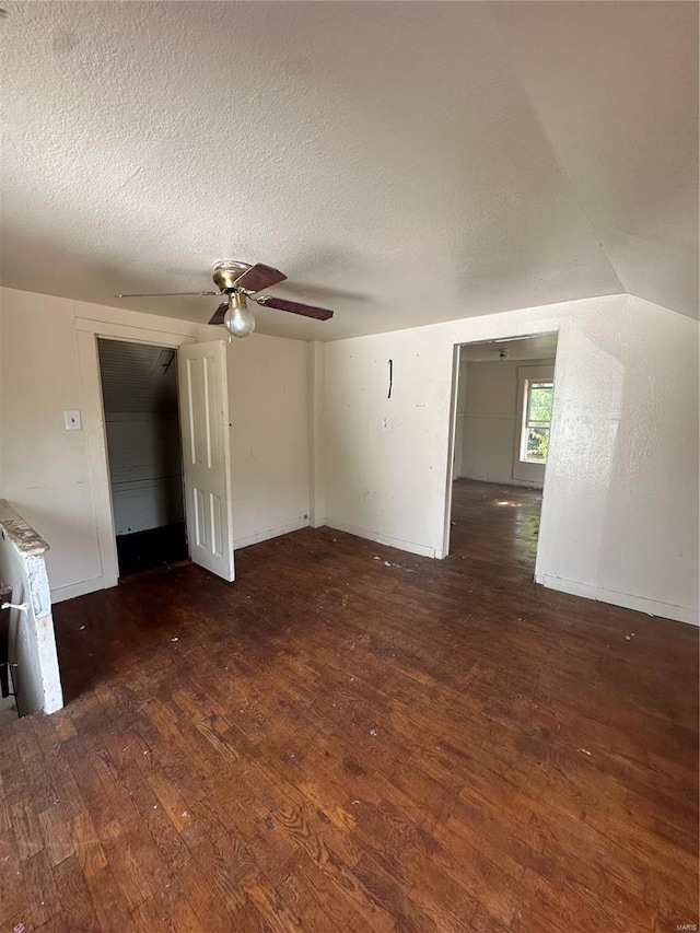 interior space with ceiling fan, vaulted ceiling, dark hardwood / wood-style flooring, and a textured ceiling