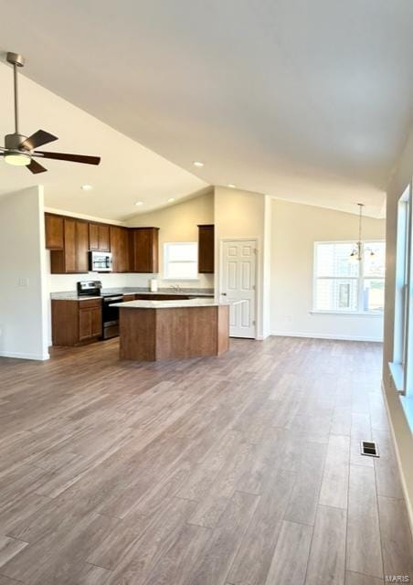 kitchen featuring wood-type flooring, appliances with stainless steel finishes, a center island, hanging light fixtures, and lofted ceiling