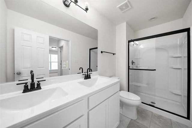 bathroom with a shower with door, vanity, toilet, and tile patterned flooring