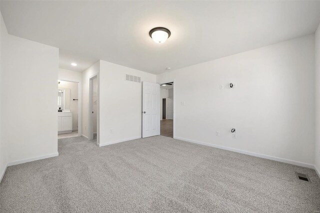 unfurnished bedroom with light colored carpet and ensuite bath