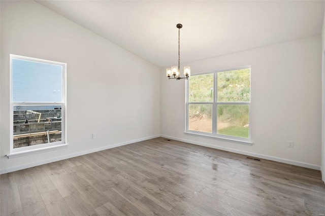 empty room with light wood-type flooring and a chandelier