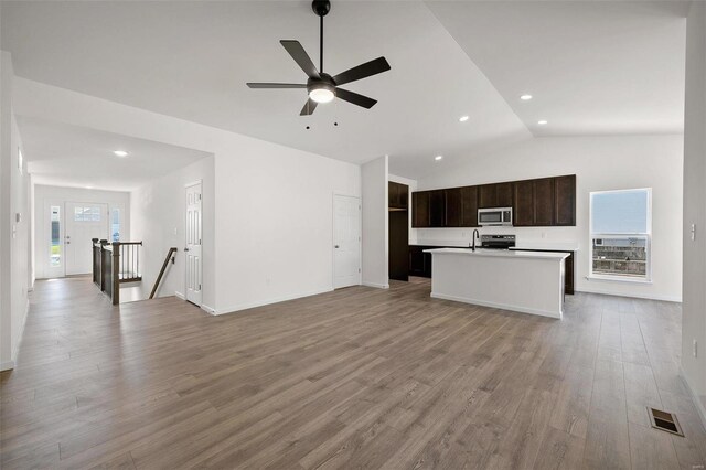 unfurnished living room featuring light wood-type flooring, ceiling fan, plenty of natural light, and vaulted ceiling