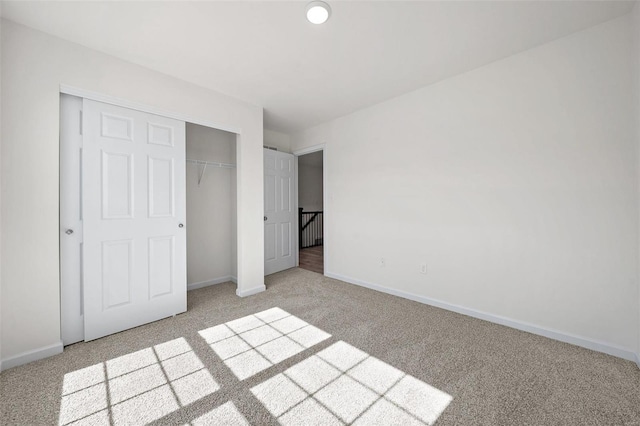 unfurnished bedroom with light colored carpet and a closet