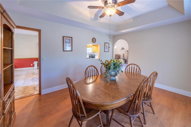 dining room featuring light hardwood / wood-style flooring, ceiling fan, and a tray ceiling