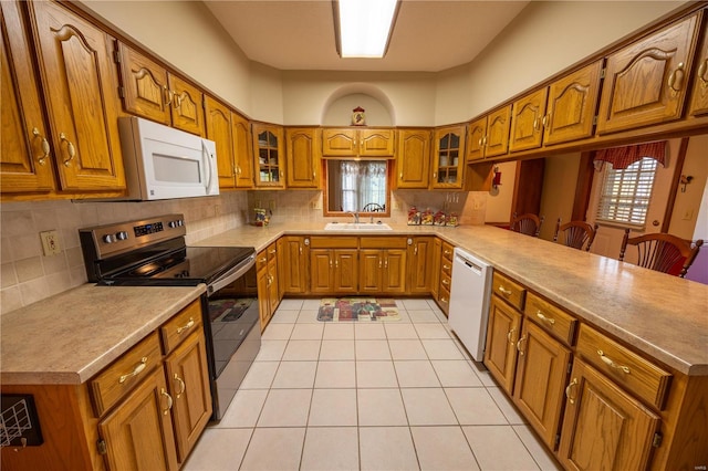 kitchen featuring white appliances, kitchen peninsula, sink, and decorative backsplash