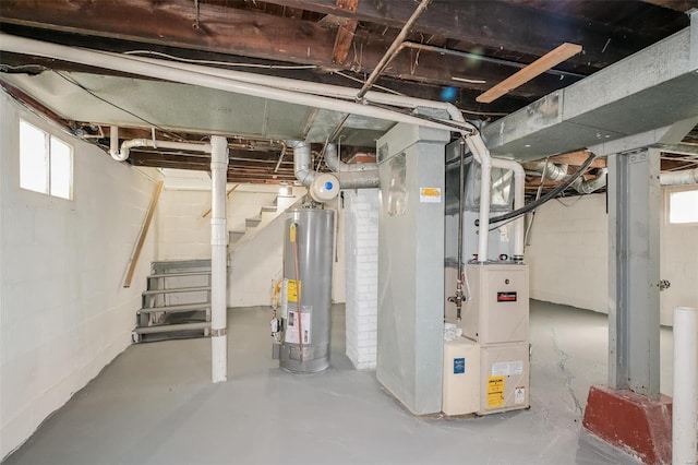 basement featuring a healthy amount of sunlight, water heater, and heating unit