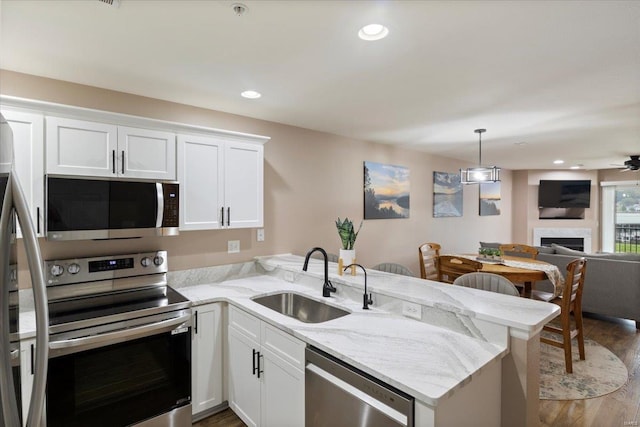 kitchen featuring white cabinets, kitchen peninsula, stainless steel appliances, and sink