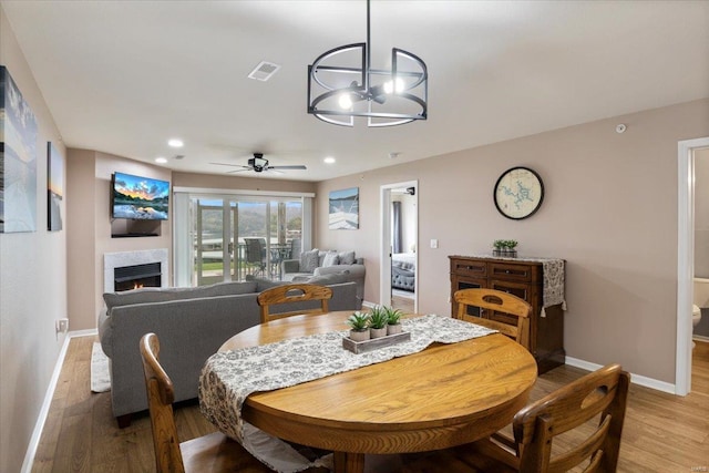 dining room featuring ceiling fan with notable chandelier and light wood-type flooring