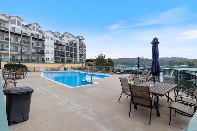 view of pool with a water view and a patio