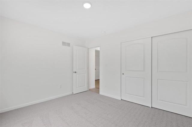 unfurnished bedroom featuring light colored carpet and a closet