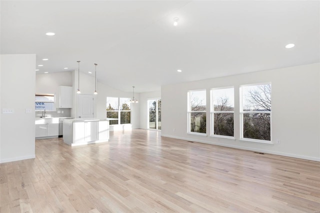 unfurnished living room with light hardwood / wood-style flooring, vaulted ceiling, and sink