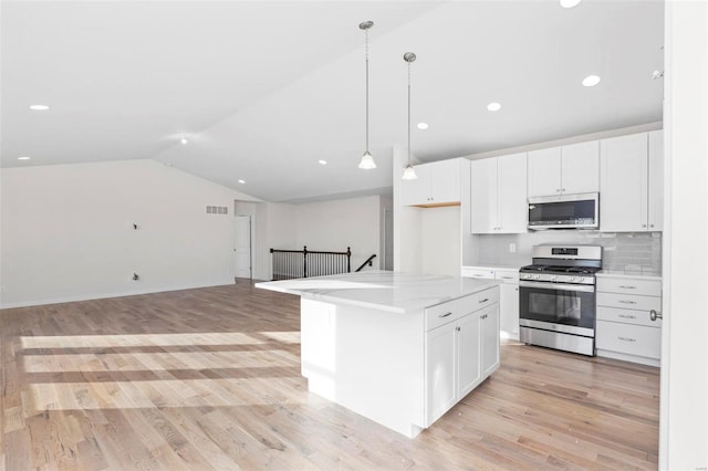 kitchen with light wood-type flooring, a kitchen island, stainless steel appliances, and white cabinets