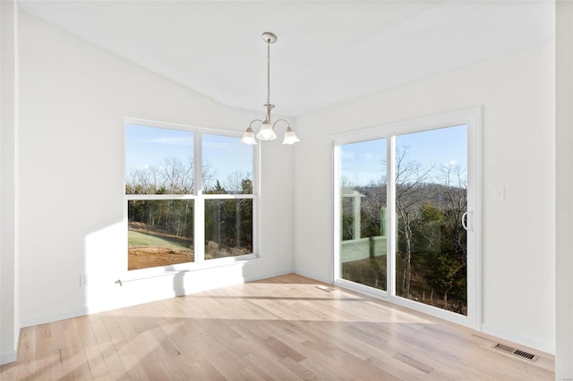 unfurnished dining area featuring lofted ceiling, light hardwood / wood-style flooring, and an inviting chandelier