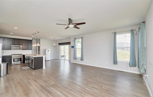 kitchen featuring a wealth of natural light, hardwood / wood-style floors, stainless steel appliances, and a center island with sink